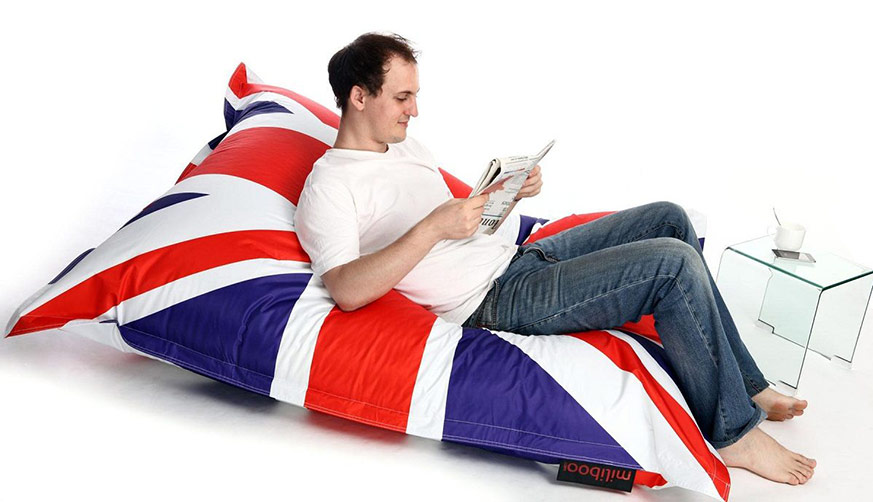 puff originales: hombre leyendo sentado sobre un puff con la bandera de Reino Unido dibujada.