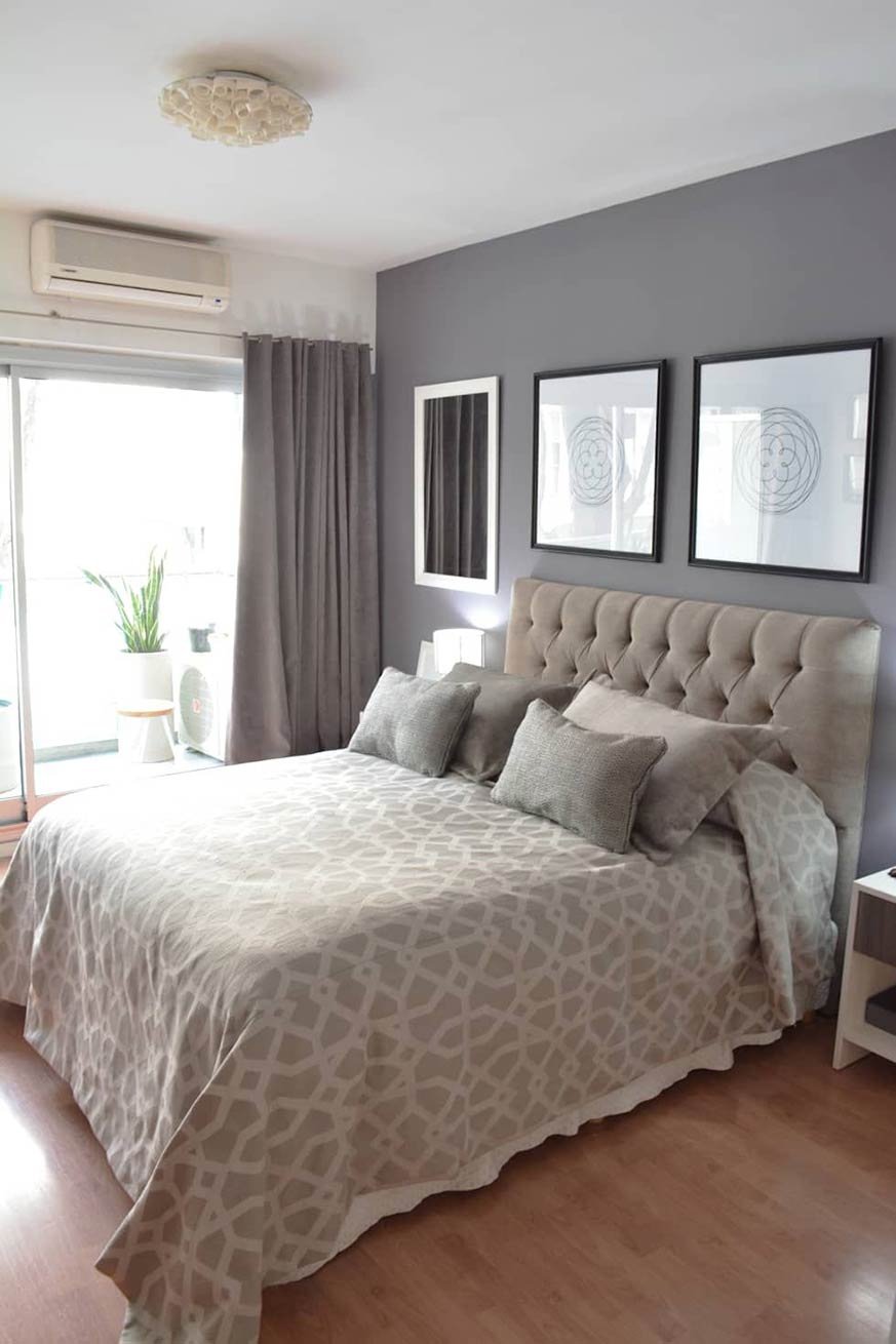 Dormitorio con que cuenta con una cama con un cabecero y cuatro cojines en color beige